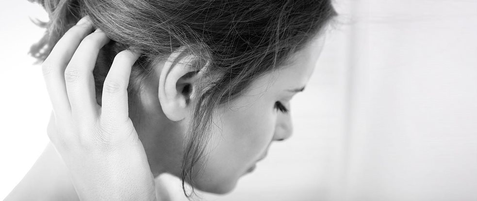 A woman in discomfort, touching her scalp