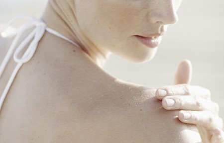 Frau trägt Hautpflege auf die rechte Schulter auf.