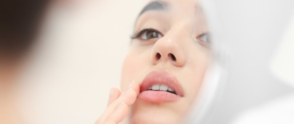 Frau mit perioraler Dermatitis im Spiegel